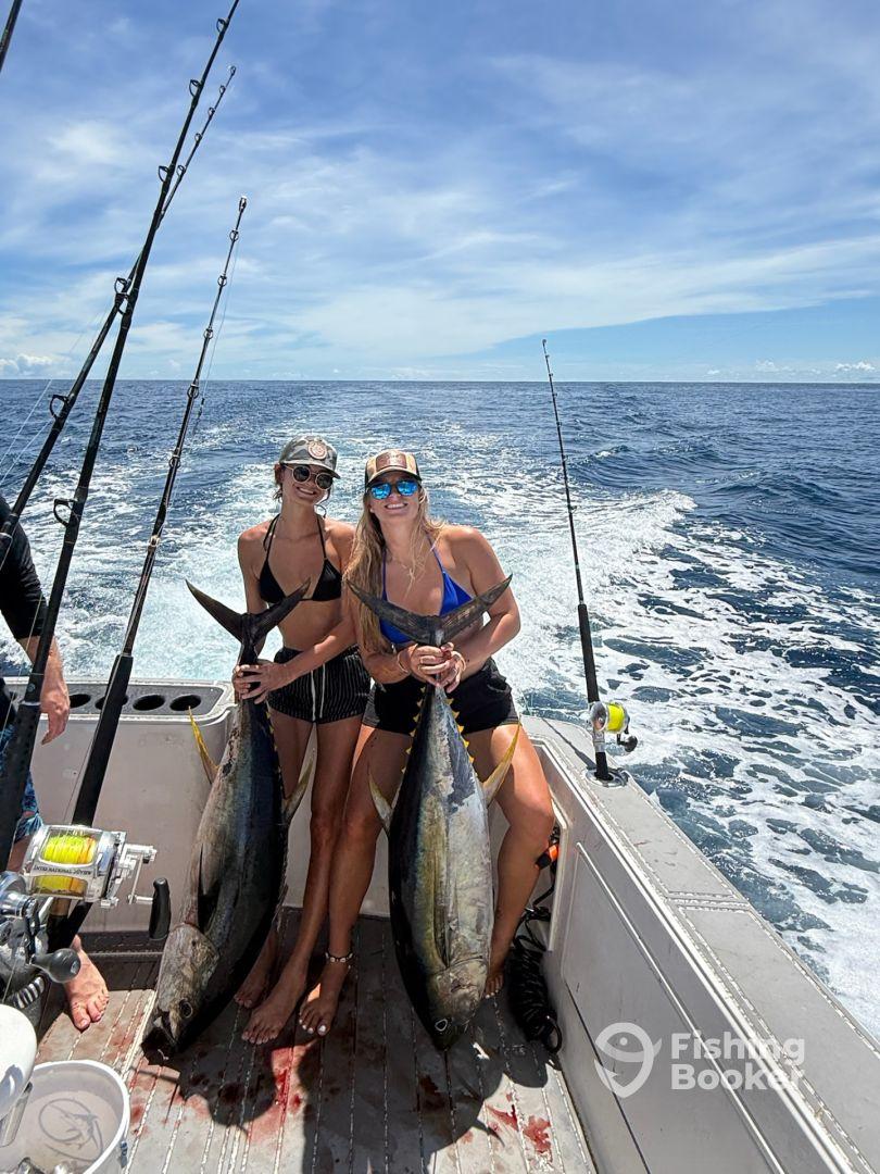 Two anglers proudly displaying their large Yellowfin Tuna on a sport fishing boat, enjoying a successful day on the open ocean.
