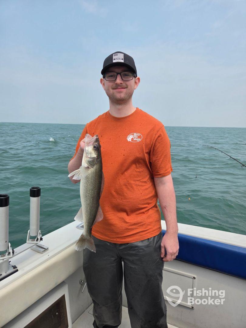 A young angler proudly displaying a Walleye caught while fishing on a boat in open water.