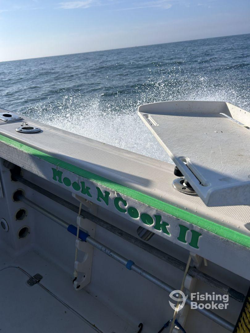 Interior view of the 'Hook N Cook II' boat, showcasing the helm area and the ocean backdrop, ideal for a day of fishing.