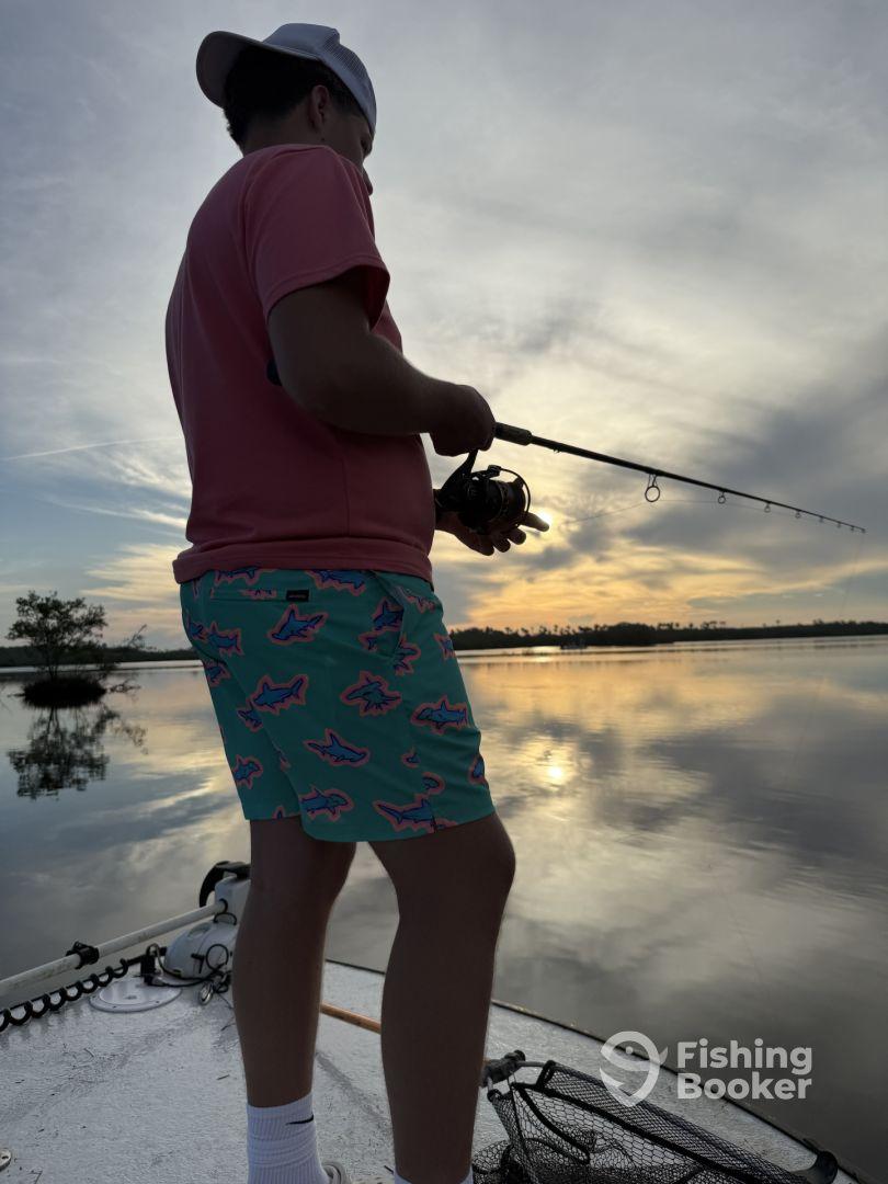 A young angler casting a line during sunset on a tranquil waterway, showcasing the excitement of fishing.