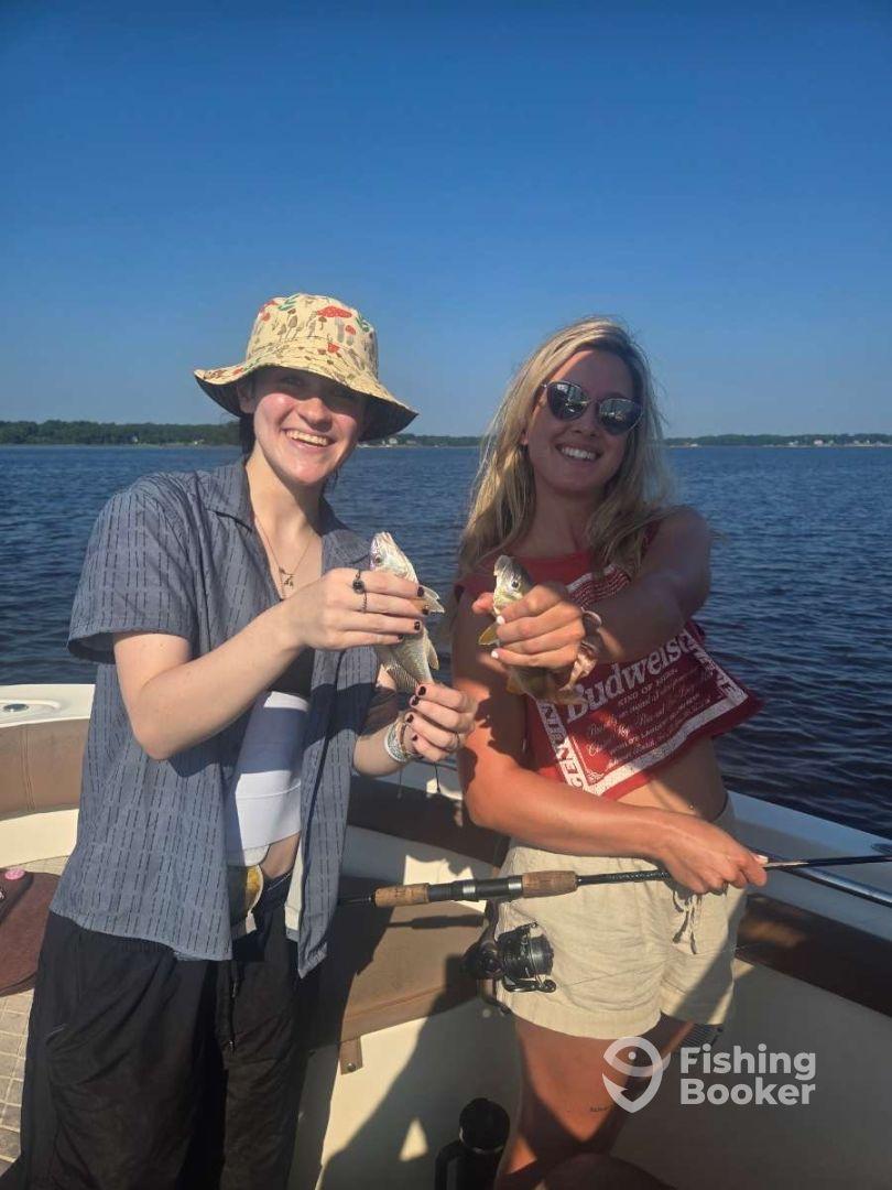 Two anglers proudly displaying their catch of small fish while enjoying a sunny day on the water.