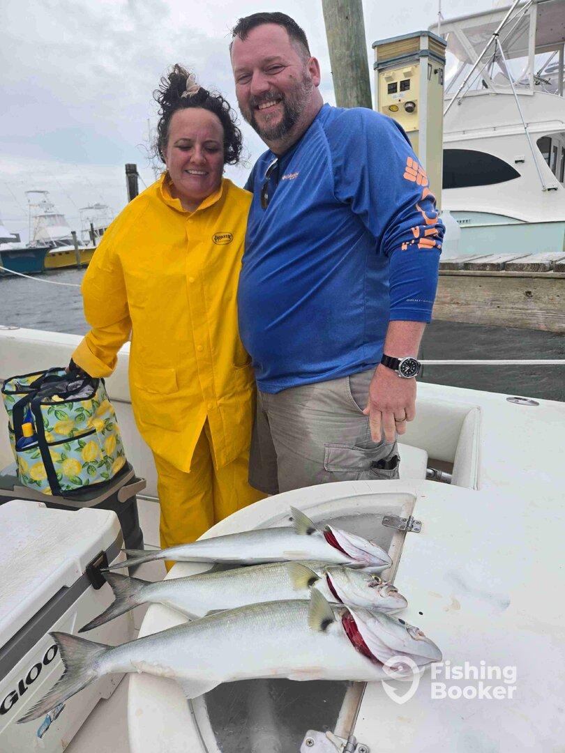 Two anglers smiling together on a boat, showcasing their catch of three Silverfish after a successful fishing trip.