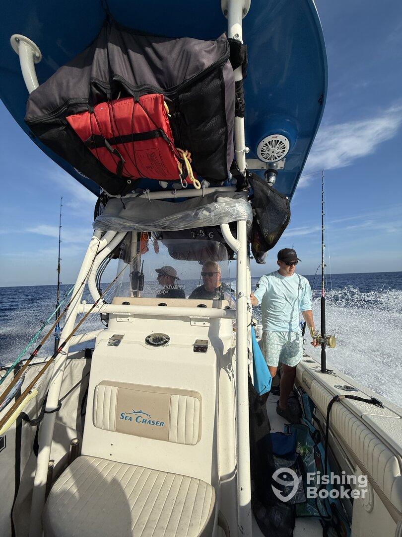 Interior view of a 'Sea Chaser' boat, showcasing the helm and seating area with anglers preparing for fishing.