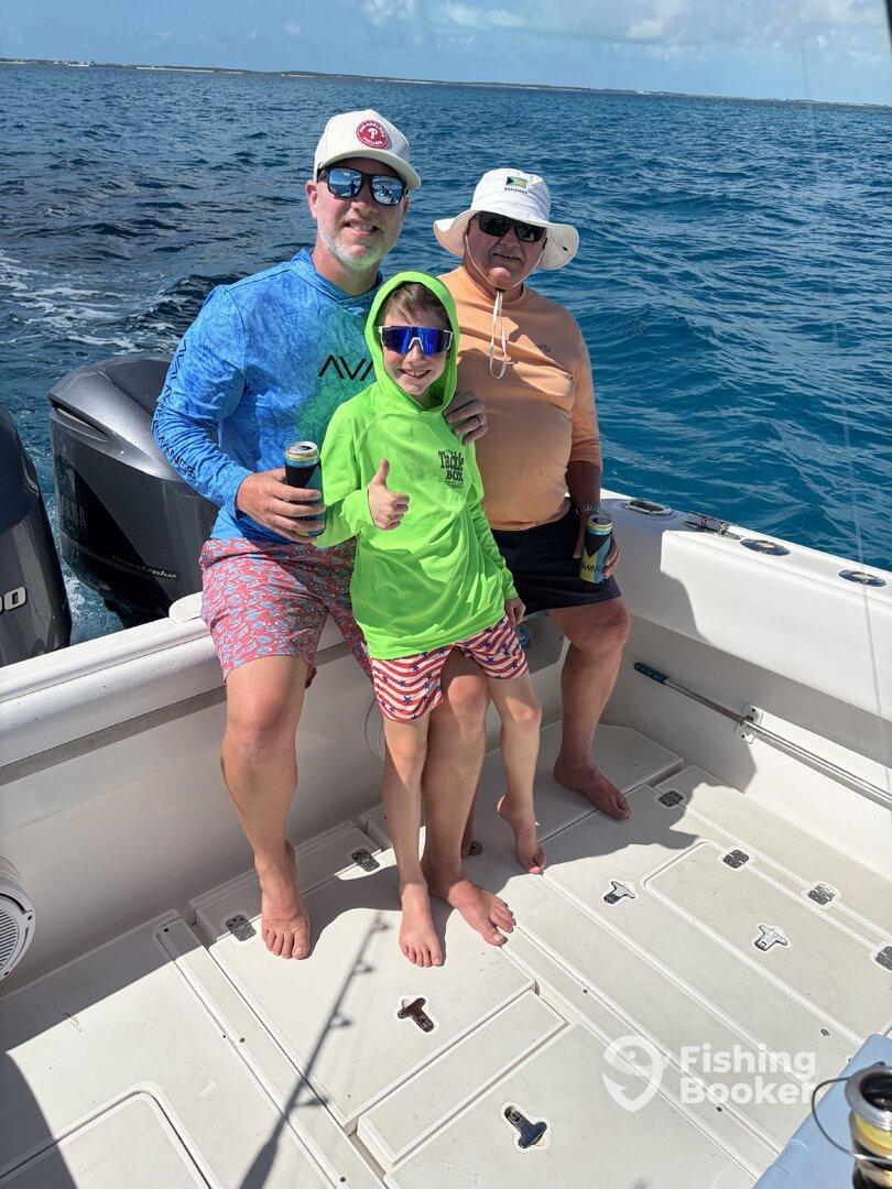 A family enjoying a fishing trip on a boat, with a young boy giving a thumbs up while seated between two adults.