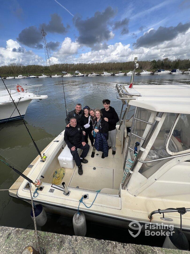 A cheerful group of six enjoying their time on a fishing boat, showcasing the comfortable seating and relaxed atmosphere.