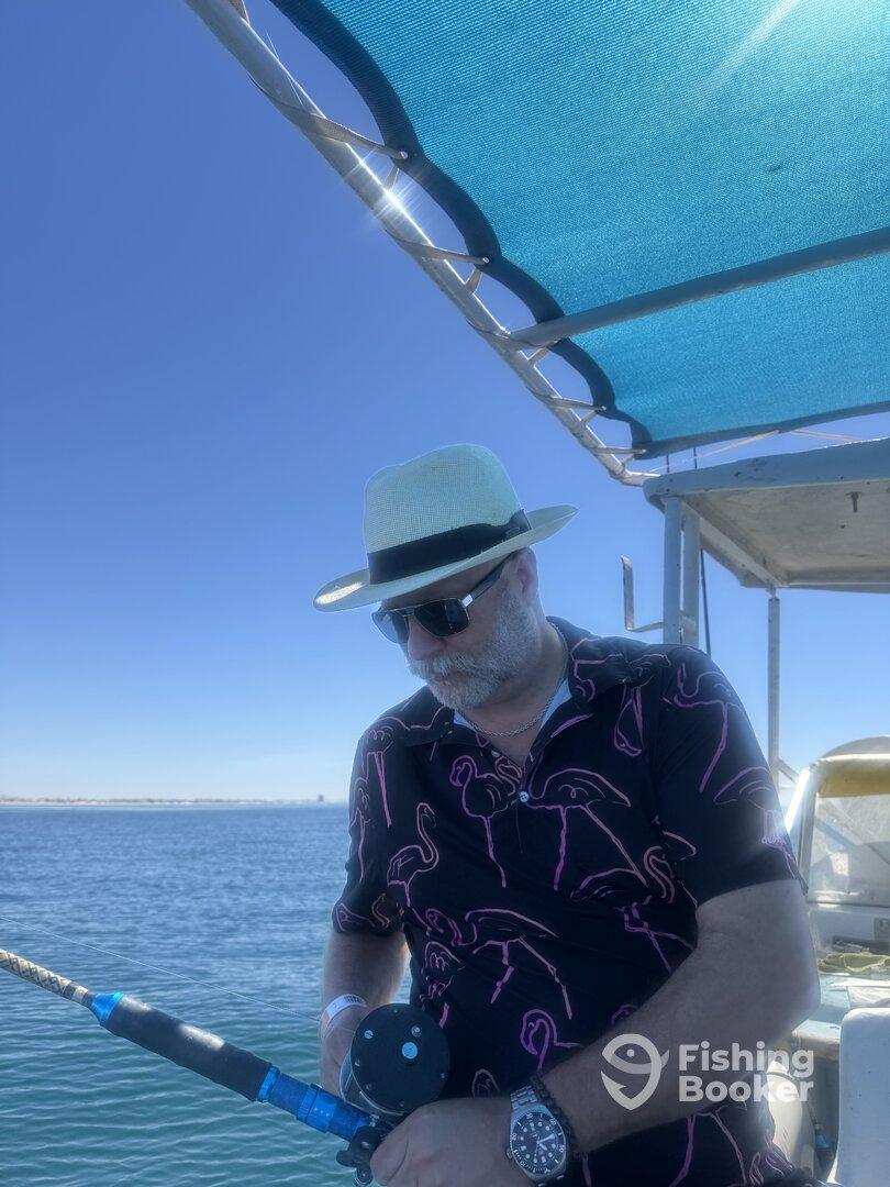 An angler focused on reeling in a catch while fishing on a sunny day, showcasing a relaxed atmosphere on the water.