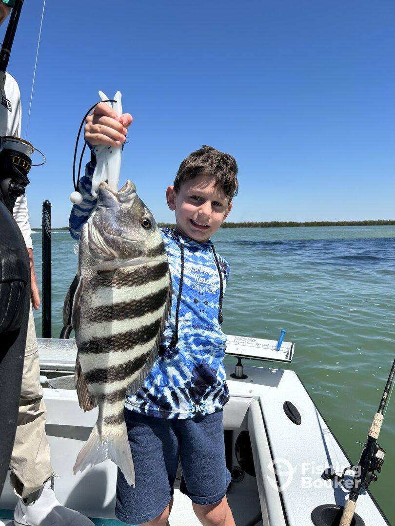 A young angler proudly displaying a large striped bass while fishing on a sunny day.
