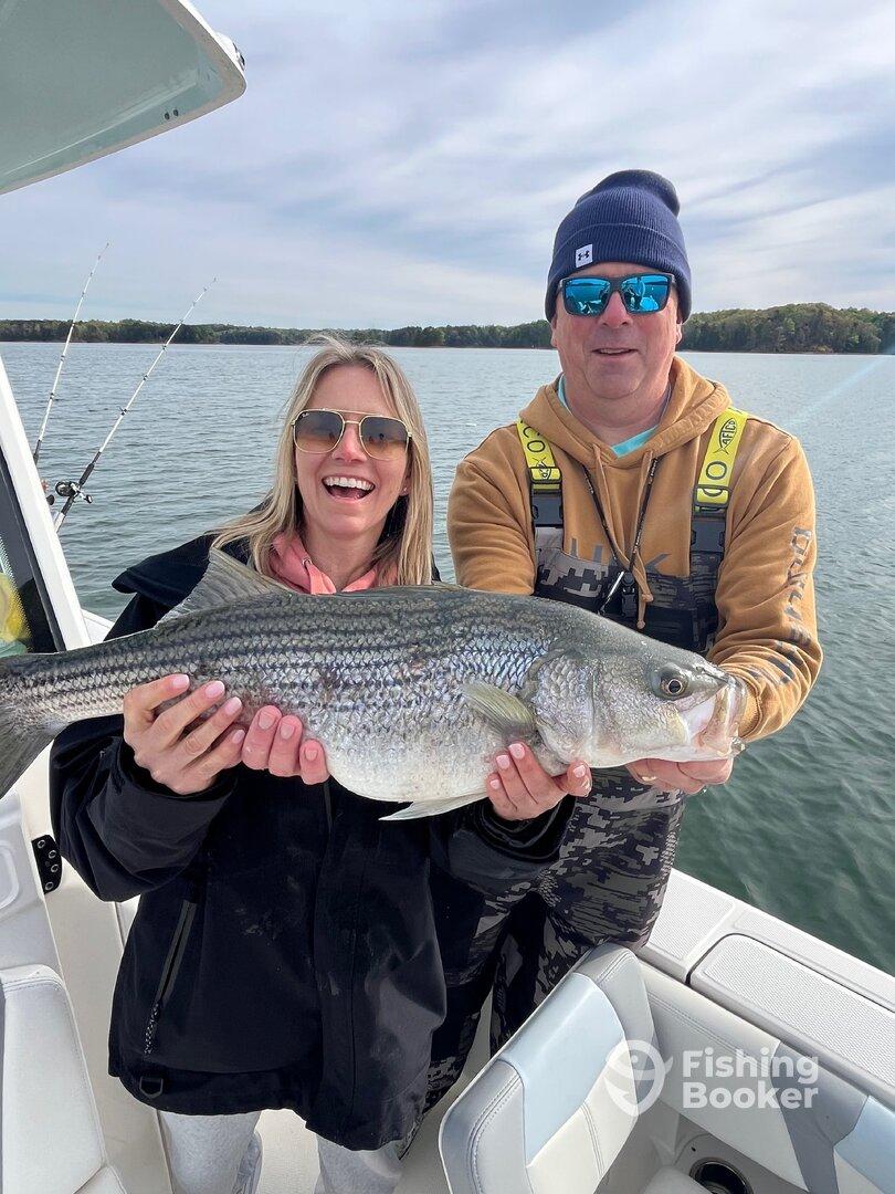 Happy anglers displaying a large Striped Bass while enjoying a day on the water.
