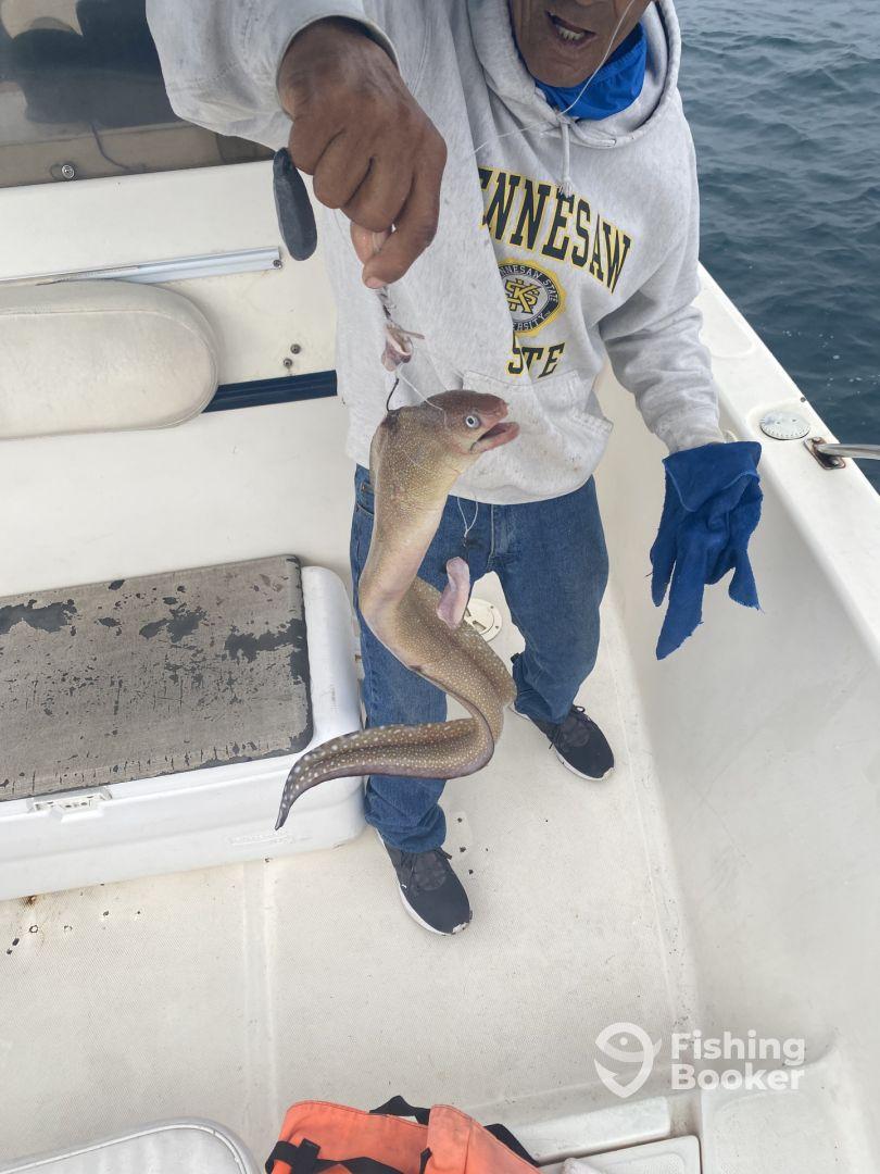 An angler proudly displaying a freshly caught fish aboard a fishing boat, showcasing the excitement of a successful fishing trip.