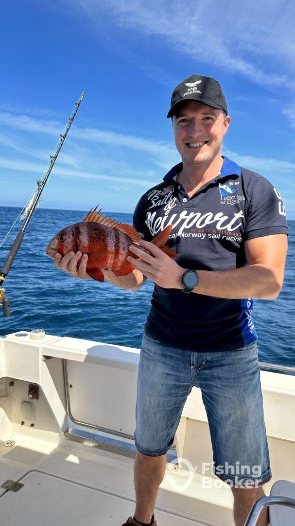 Angler proudly displaying a vibrant Red Snapper while fishing offshore, showcasing a successful day on the water.