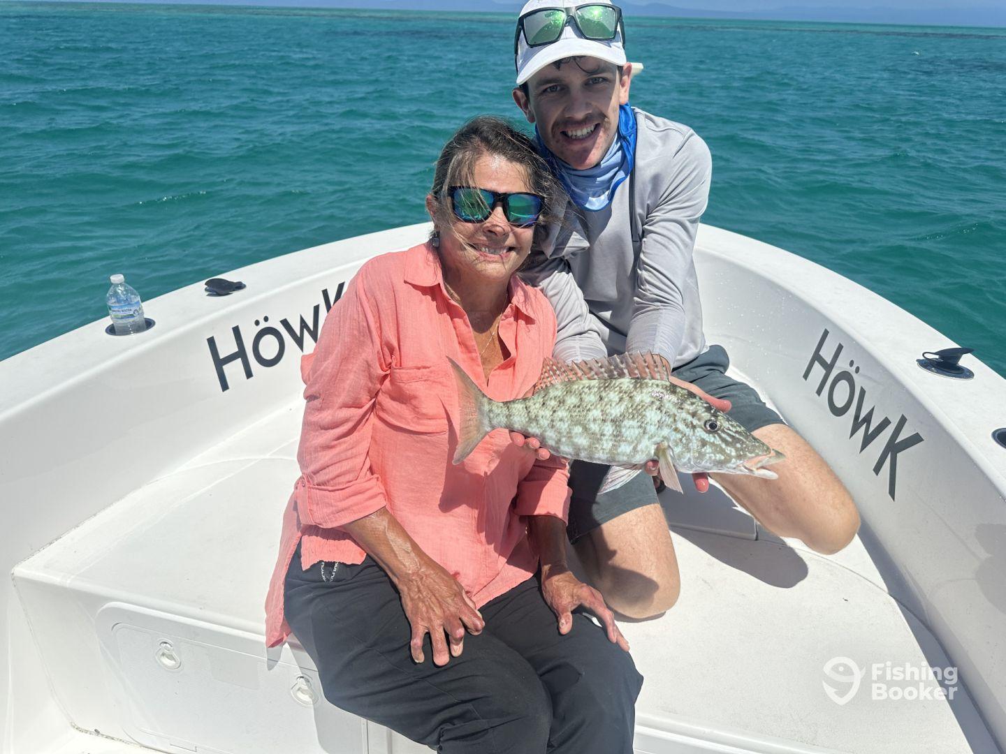 A proud moment on the boat as an angler holds up a beautiful Grouper caught during a sunny fishing trip.