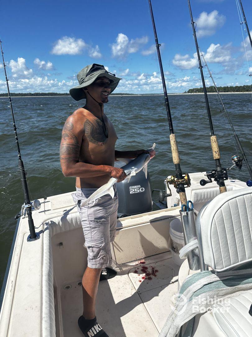 Angler holding a freshly caught fish on a fishing boat, showcasing a successful day on the water.