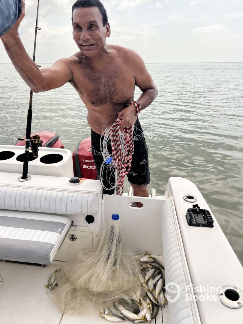 An enthusiastic angler displaying a catch of small fish aboard a boat, showcasing a successful fishing trip.