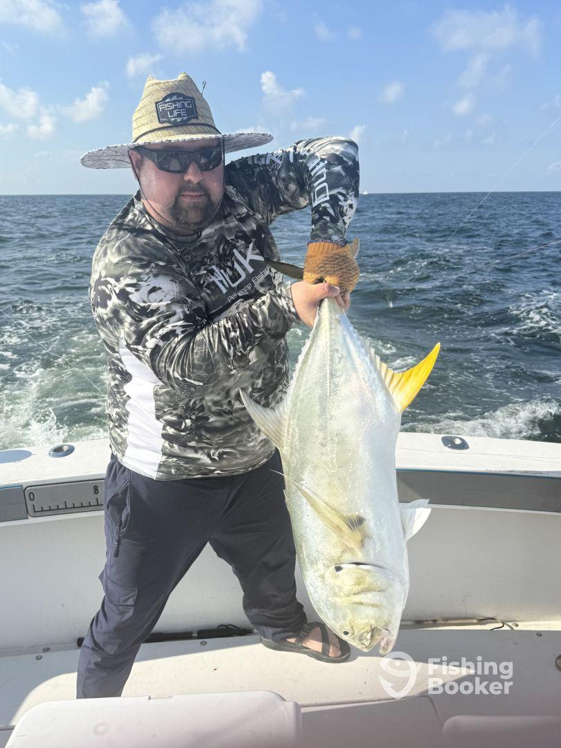 Angler proudly displaying a large Jack Crevalle while fishing offshore, showcasing the excitement of a successful catch.