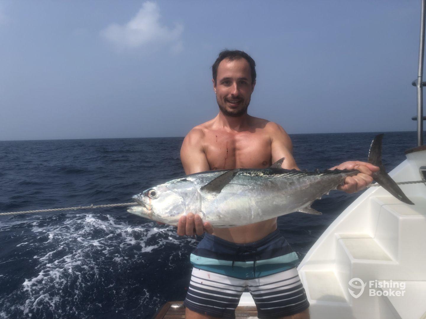 Angler proudly displaying a large Tuna while fishing offshore, showcasing the excitement of a successful catch.